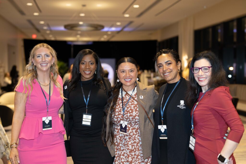 Five smiling women wearing badges at a TPC event.