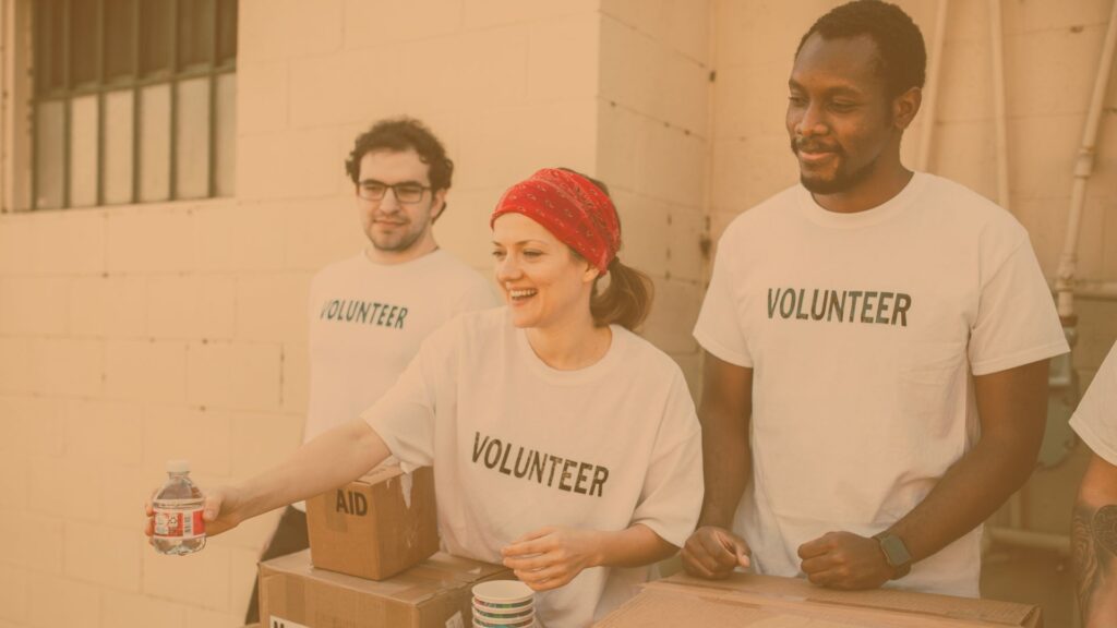Color photo with tan overlay, three people in volunteer shirts, one handing out water.
