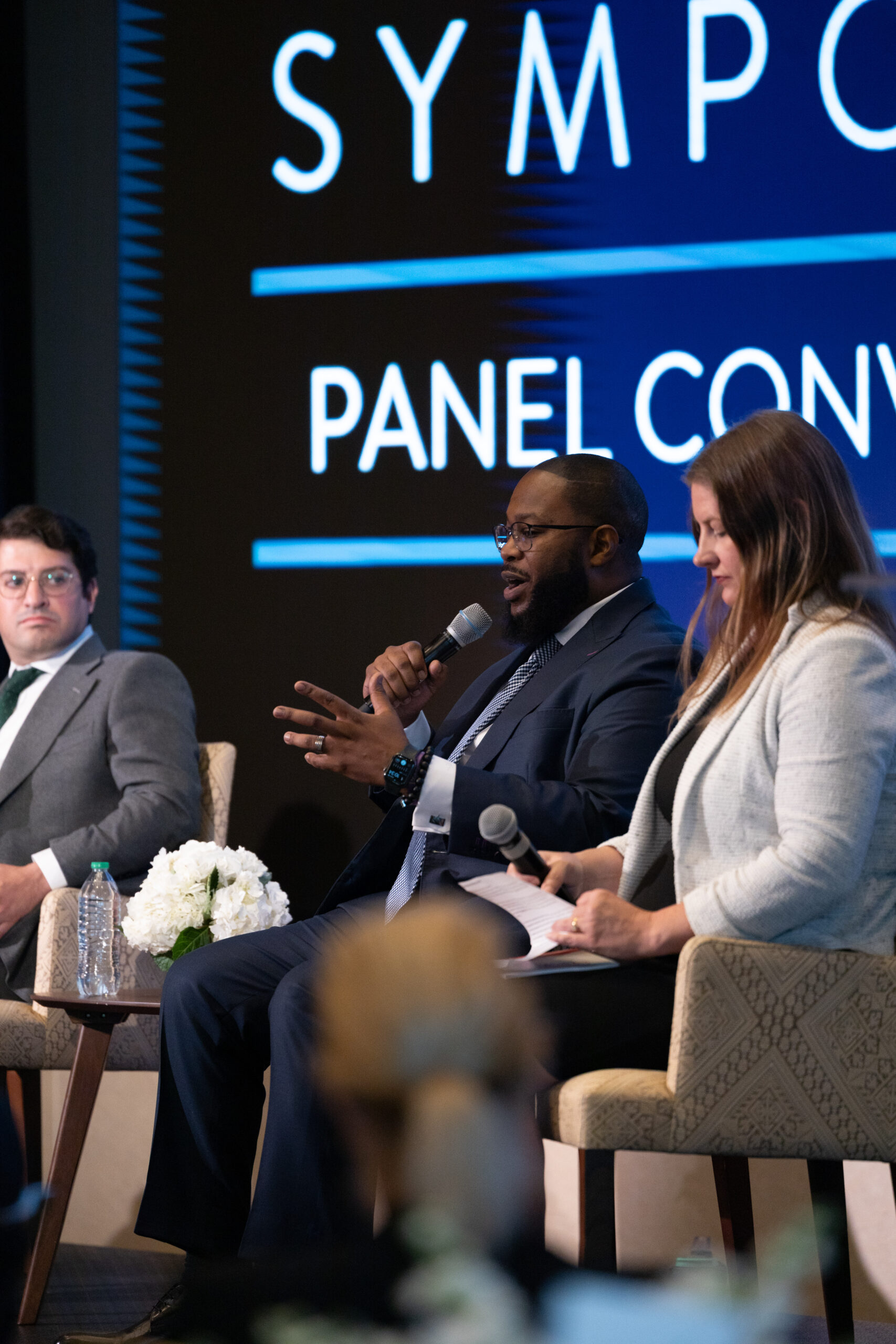 Color photo of three people on a panel with microphones at the Faith and Civic Life Symposium.