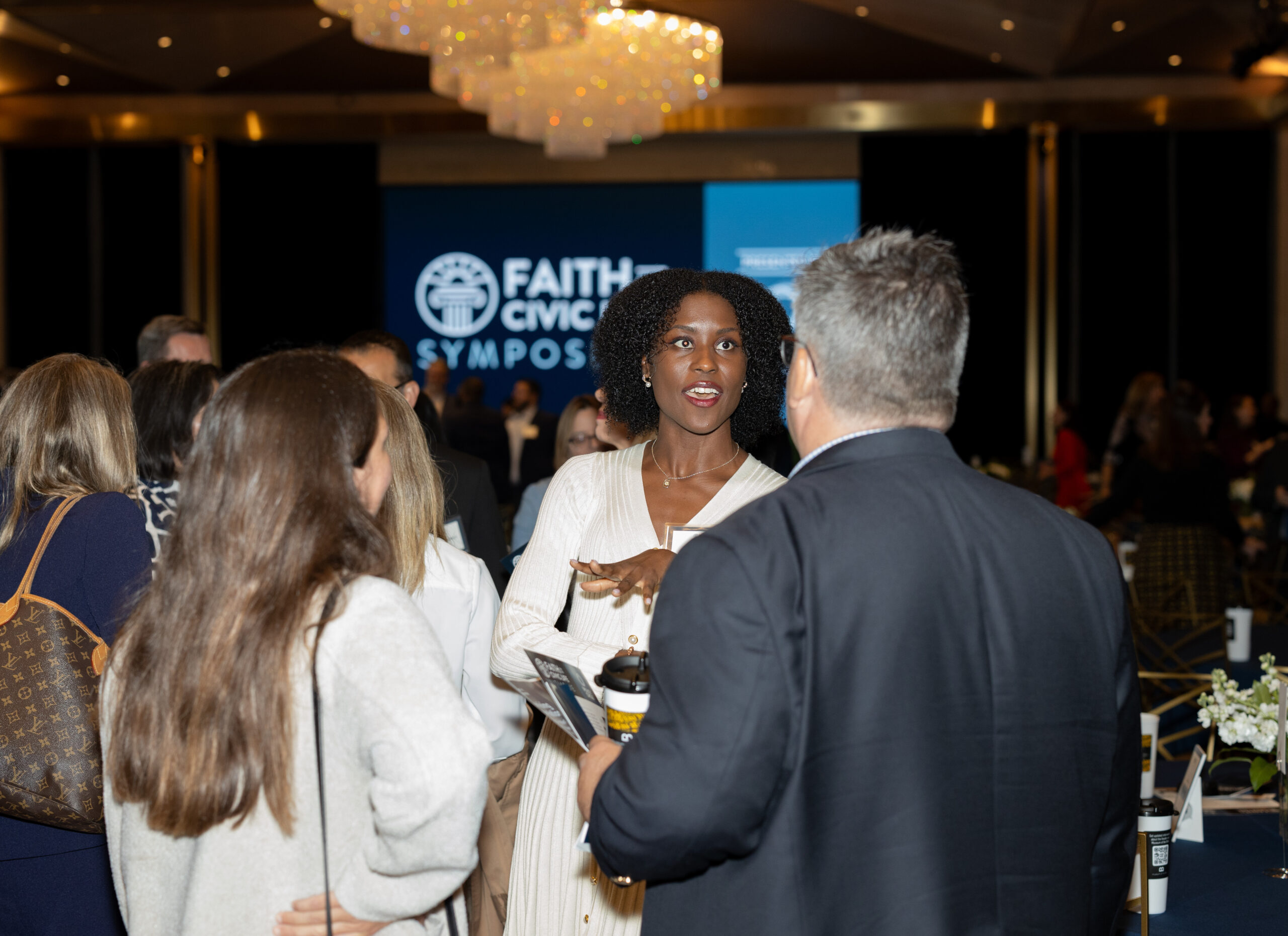 Color photo of three people conversing at the Faith and Civic Life Symposium.