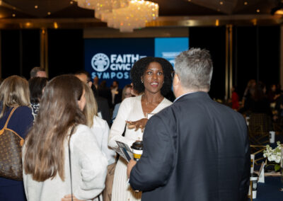 Color photo, attendees conversing at the Faith and Civic Symposium.