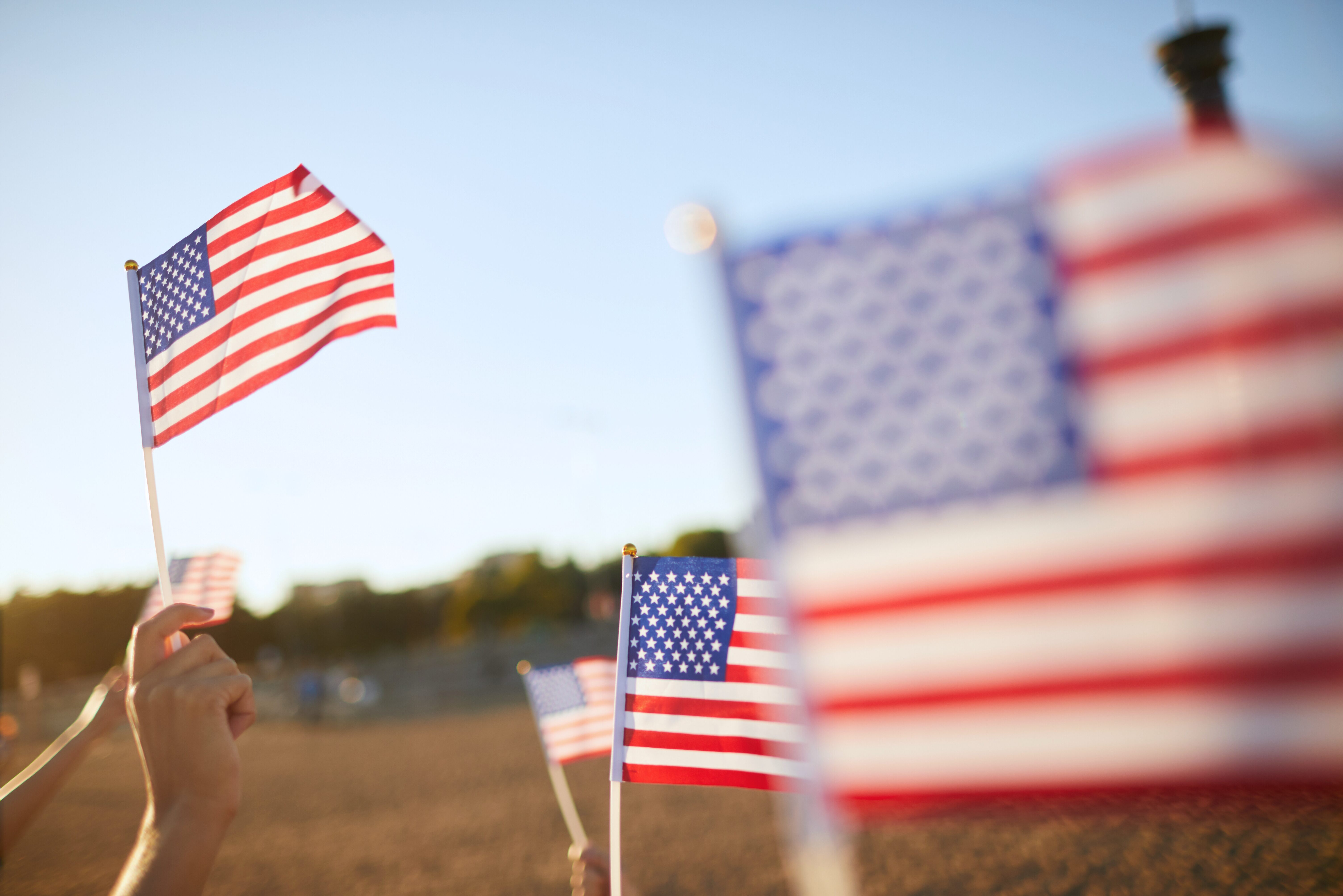 People waving American flags in a field.