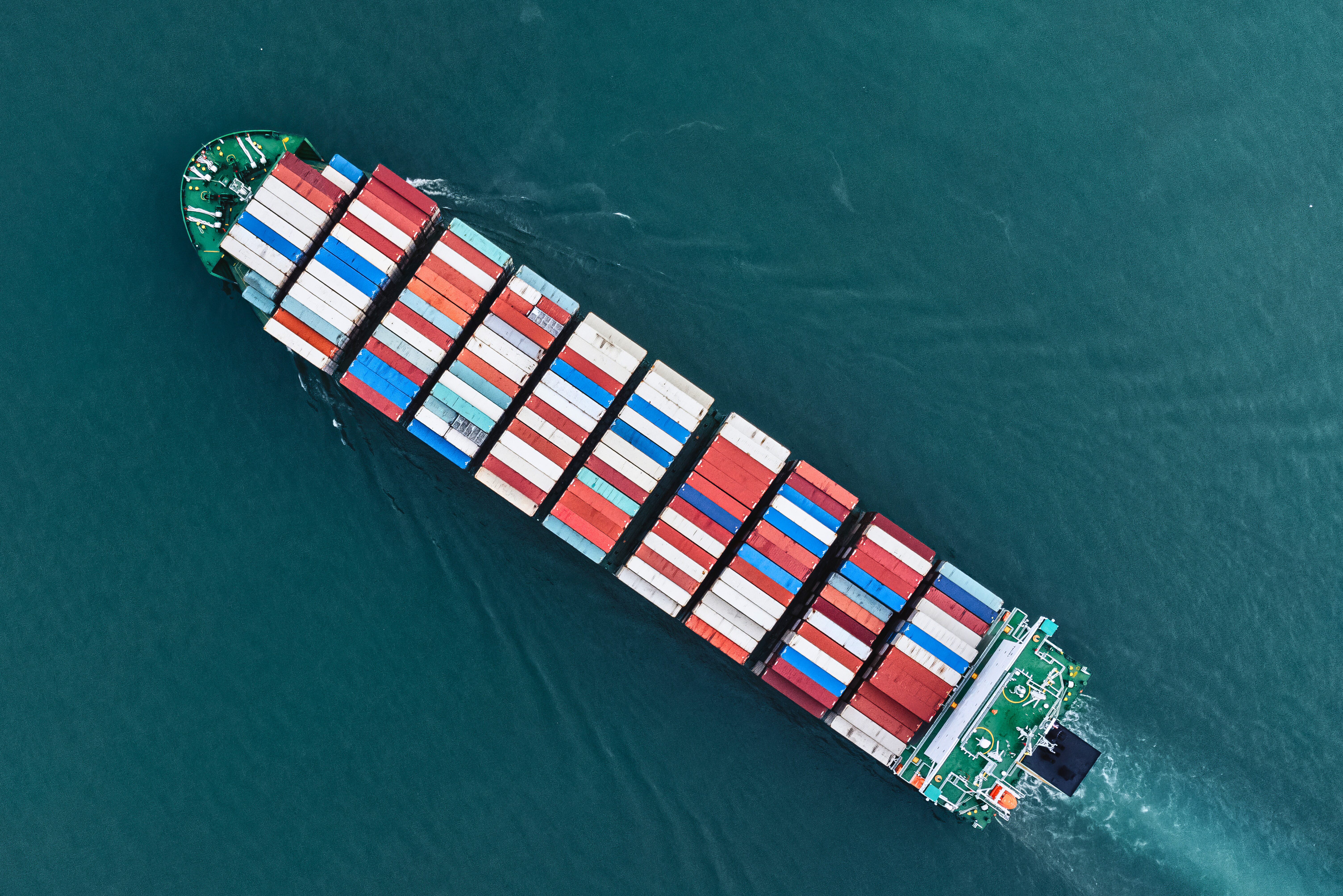 A cargo ship in the ocean with shipping containers loaded on it.
