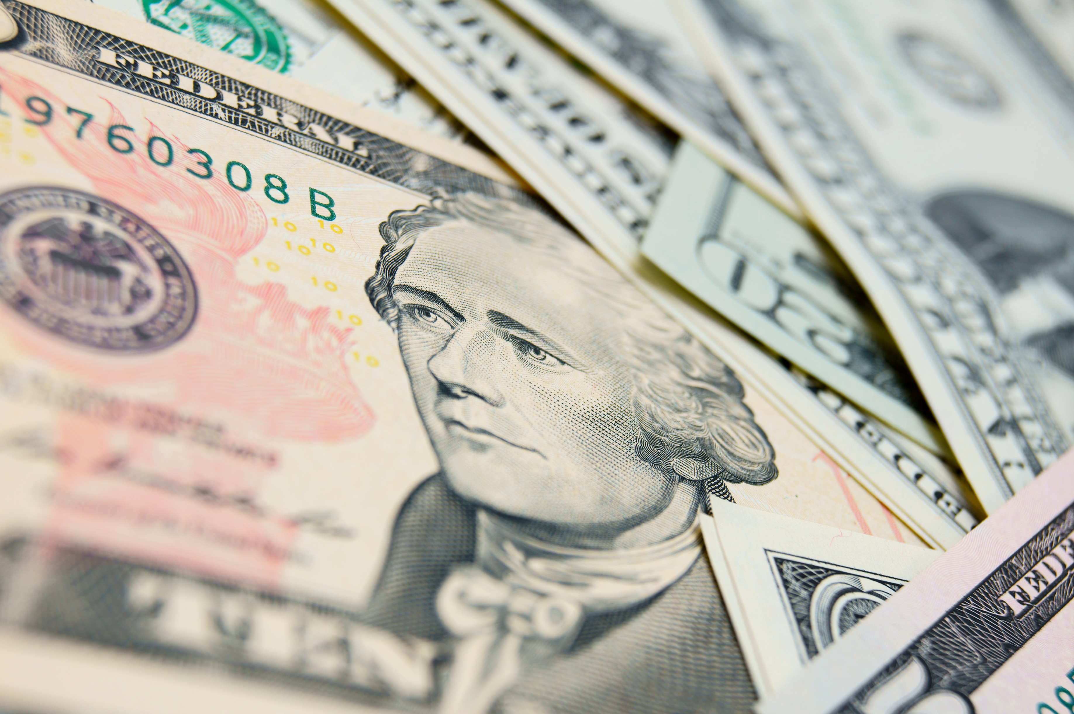 A close up of a ten dollar bill in a pile of other U.S. bills.